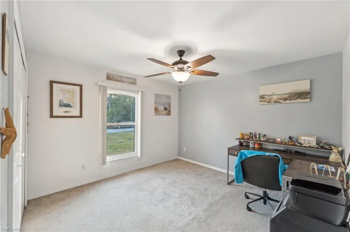 Carpeted office featuring ceiling fan