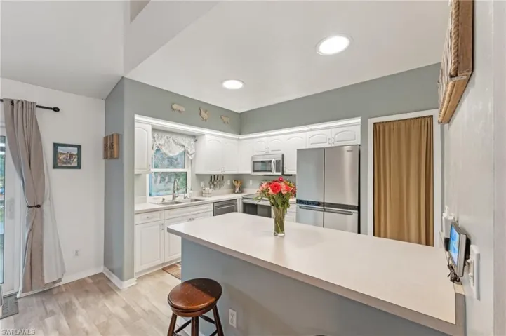 Kitchen featuring sink, white cabinets, stainless steel appliances, and light wood-type flooring