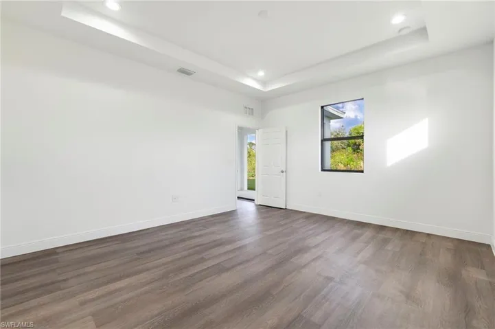 Empty room featuring dark hardwood / wood-style flooring and a tray ceiling