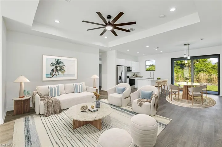 Living room featuring a raised ceiling, sink, and light hardwood / wood-style floors