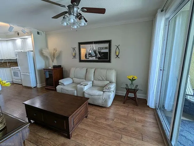 Living room with sink, wood-type flooring, crown molding, and ceiling fan