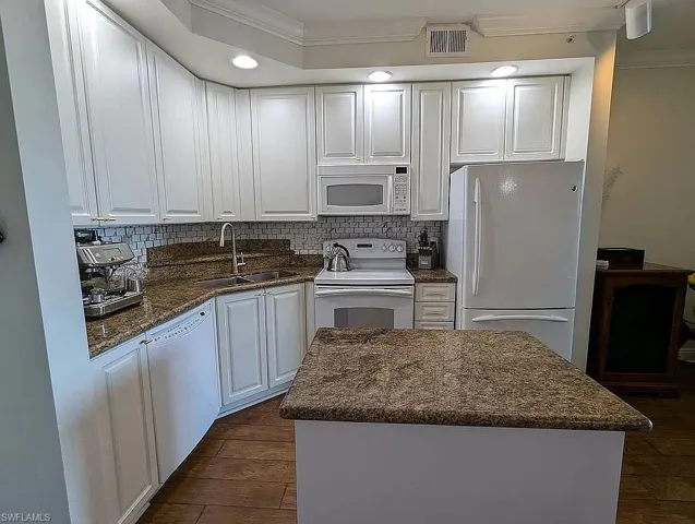 Kitchen featuring dark wood-type flooring, sink, white cabinetry, and white appliances