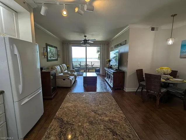 Living room featuring rail lighting, dark hardwood / wood-style floors, ceiling fan, and ornamental molding