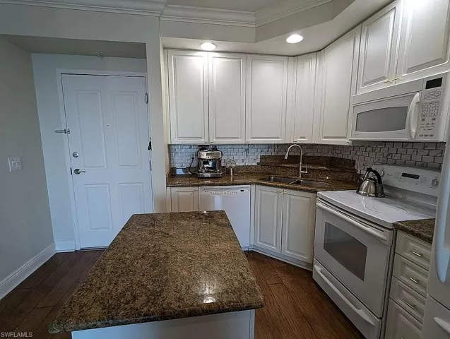Kitchen featuring sink, dark wood-type flooring, white appliances, and white cabinets