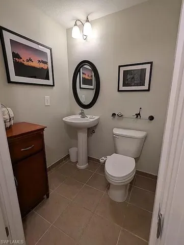 Bathroom with tile patterned flooring, toilet, and a textured ceiling