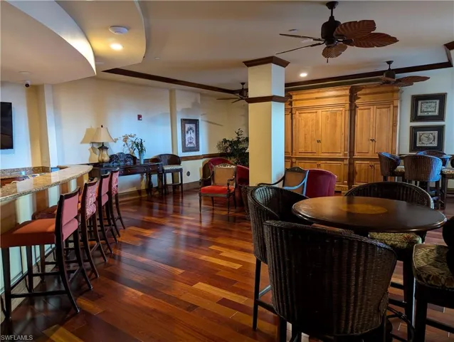 Common space with dark hardwood / wood-style floors, crown molding, and ceiling fan
