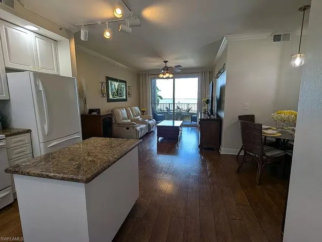 Kitchen featuring white refrigerator, ceiling fan, white cabinets, rail lighting, and dark wood-type flooring