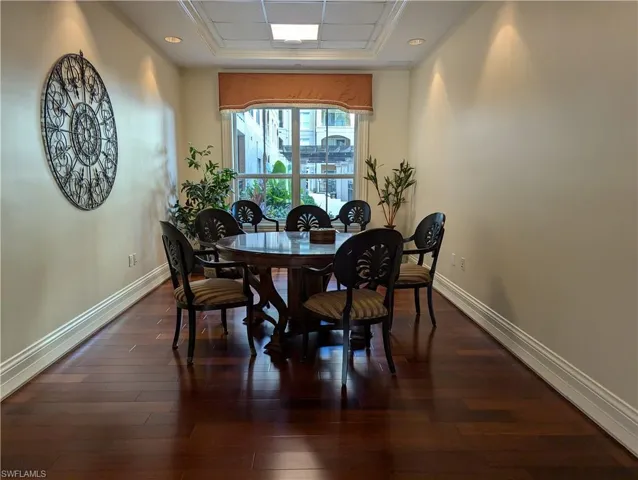 Dining space with dark hardwood / wood-style flooring and a raised ceiling