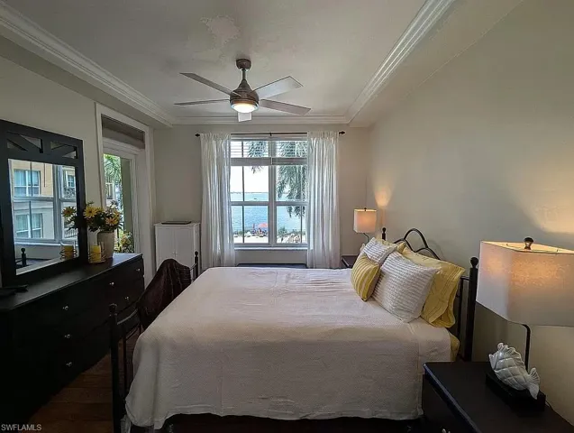 Bedroom with multiple windows, wood-type flooring, ceiling fan, and crown molding