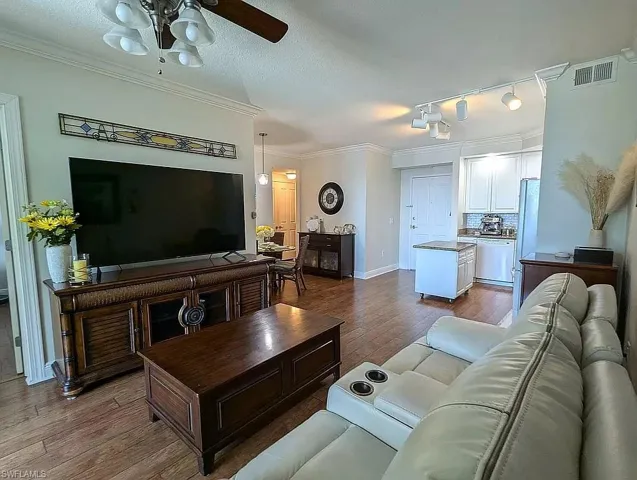 Living room featuring ornamental molding, wood-type flooring, and ceiling fan