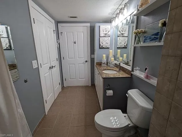 Bathroom with vanity, a textured ceiling, tile patterned flooring, and toilet