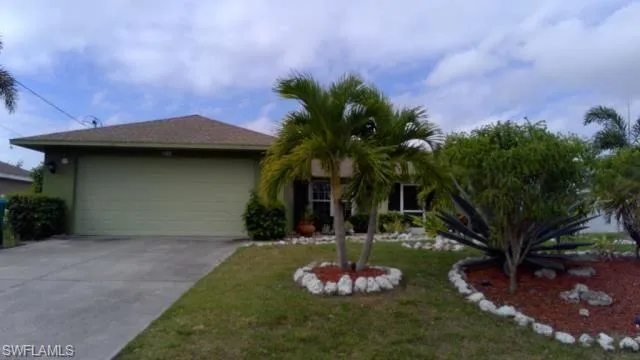 Single story home with a garage and a front lawn