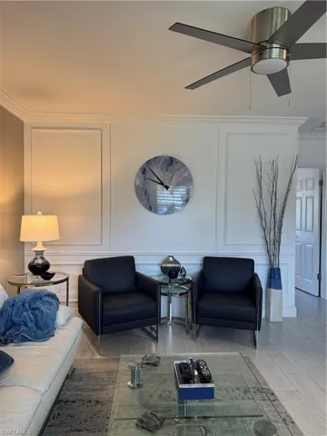 Sitting room featuring a decorative wall, a ceiling fan, and crown molding