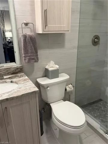 Full bath featuring tile walls, tiled shower, and vanity