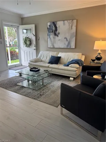 Living room with crown molding and light wood-style ceramic floors