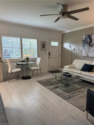 Living area with light light ceramic tile floors, crown molding, and ceiling fan