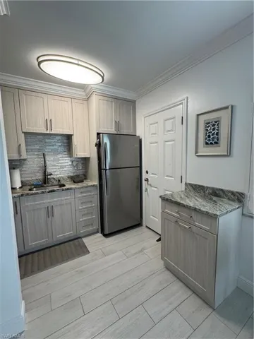 Custom Kitchen with Upscale cabinetry to ceiling, granite countertops, freestanding refrigerator, ornamental crown molding, ceramic tiled floors, and tasteful backsplash