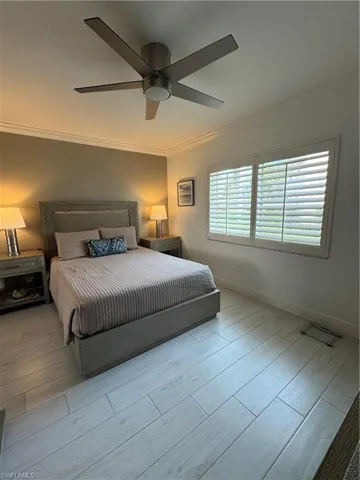 Bedroom with wood tiled floors, ornamental molding, and a ceiling fan