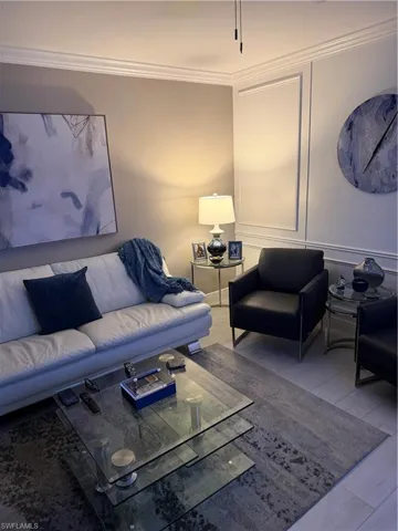Living room with ornamental molding and a decorative wall