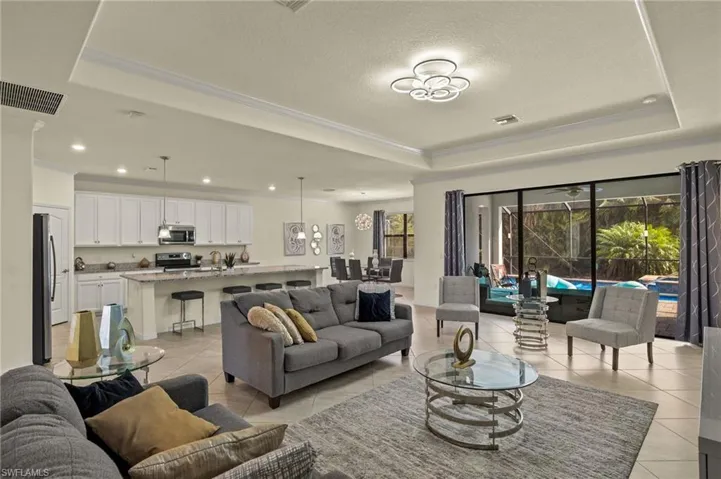 Tiled living room featuring a tray ceiling, ornamental molding, and a textured ceiling