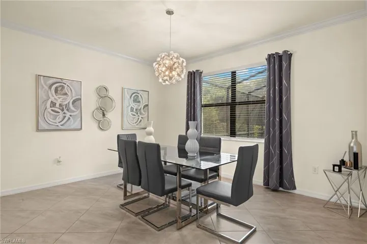 Tiled dining space featuring a chandelier and crown molding