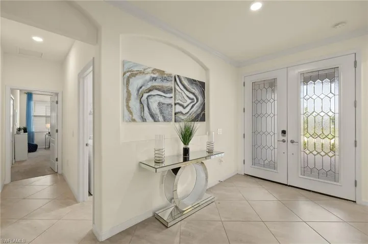 Foyer featuring ornamental molding, light tile patterned floors, french doors, and a healthy amount of sunlight