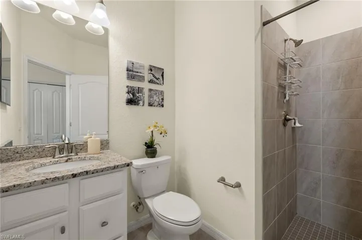 Bathroom with vanity, tiled shower, and toilet