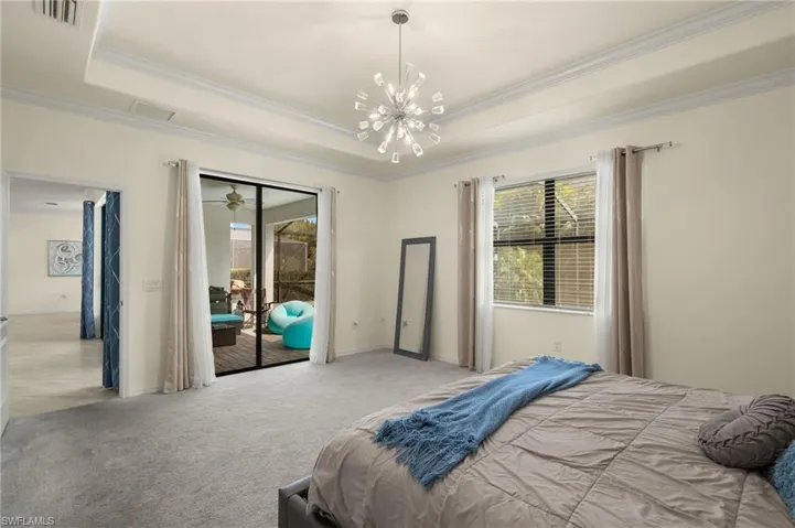 Carpeted bedroom featuring a chandelier, a tray ceiling, access to outside, and ornamental molding