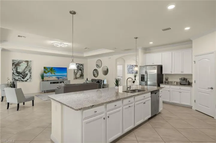 Kitchen with appliances with stainless steel finishes, sink, white cabinetry, and a kitchen island with sink