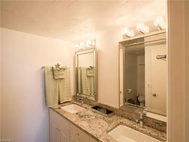 Full bathroom featuring double vanity, toilet, and a textured ceiling
