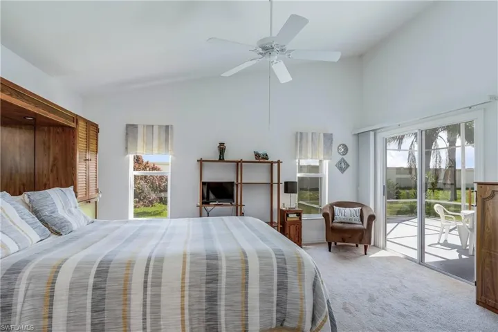 Bedroom with access to outside, carpet floors, high vaulted ceiling, and ceiling fan