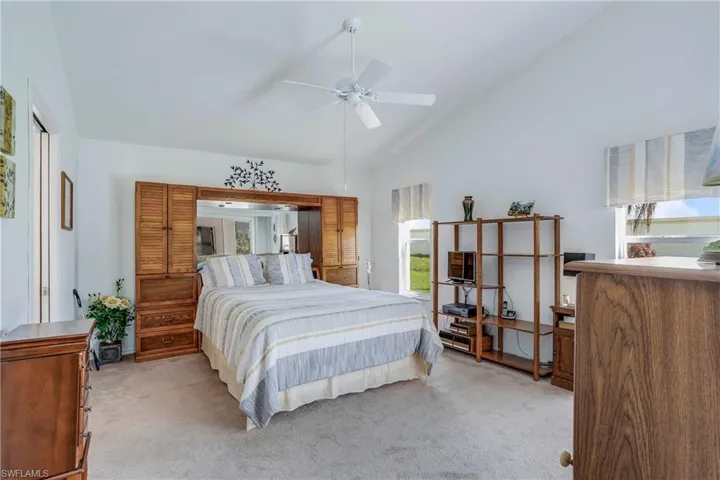 Bedroom featuring light carpet, ceiling fan, and high vaulted ceiling