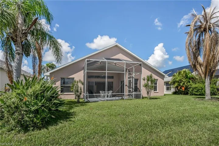 Rear view of property with a lawn and glass enclosure