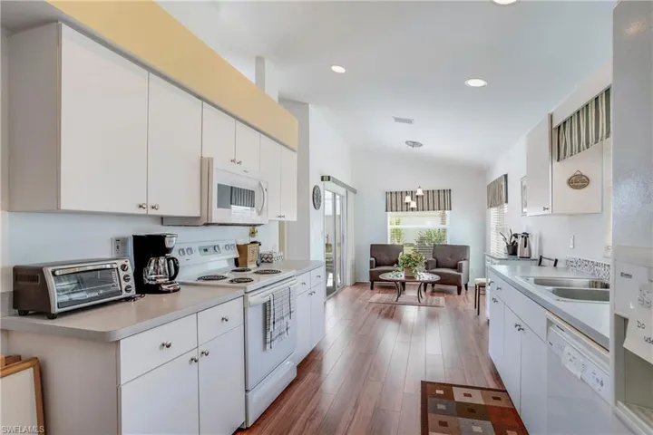 Kitchen featuring lofted ceiling, white cabinets, and white appliances