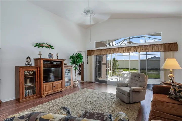 Living room with high vaulted ceiling, ceiling fan, and dark wood-type flooring
