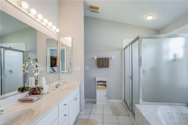 Bathroom with shower with separate bathtub, lofted ceiling, vanity, and tile patterned flooring