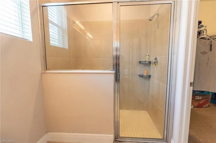 Bathroom with a walk in closet and a shower stall