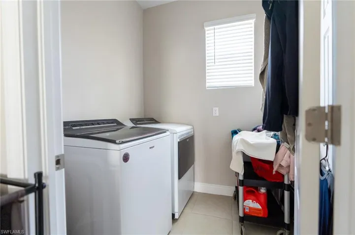 Laundry area with washing machine and dryer and light tile patterned flooring