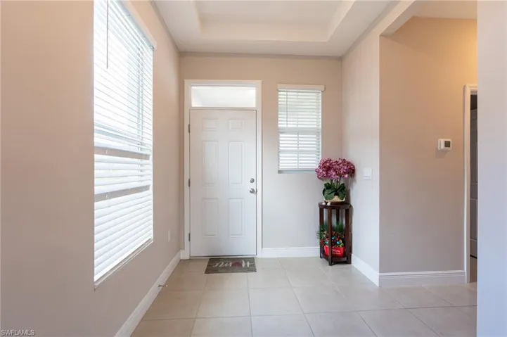 Foyer entrance with a tray ceiling and light tile patterned flooring