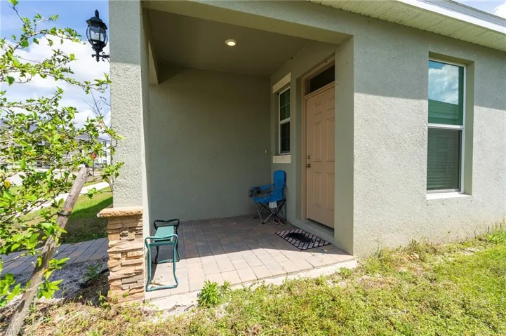 View of exterior entry with stucco siding and a patio
