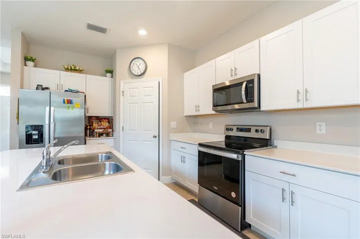 Kitchen with stainless steel appliances, white cabinets, light countertops, and recessed lighting