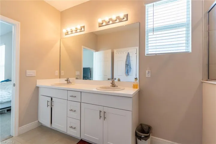 Full bath with double vanity, connected bathroom, and light tile patterned floors
