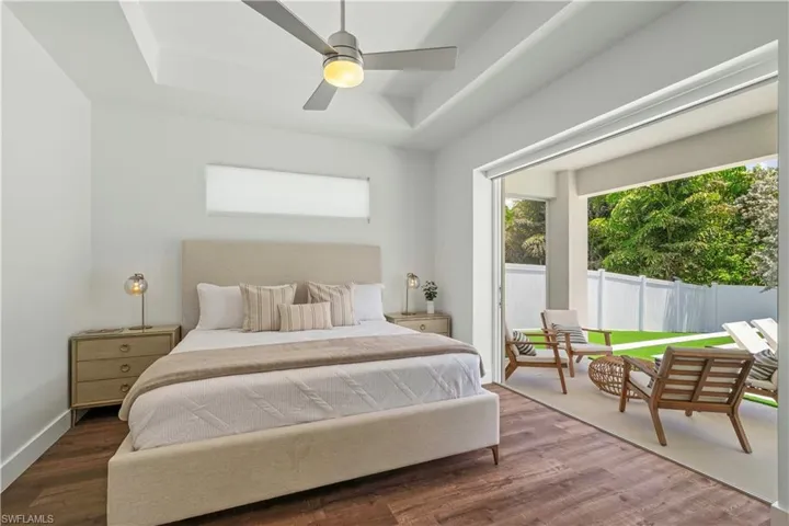 Bedroom featuring a raised ceiling, ceiling fan, and wood finished floors