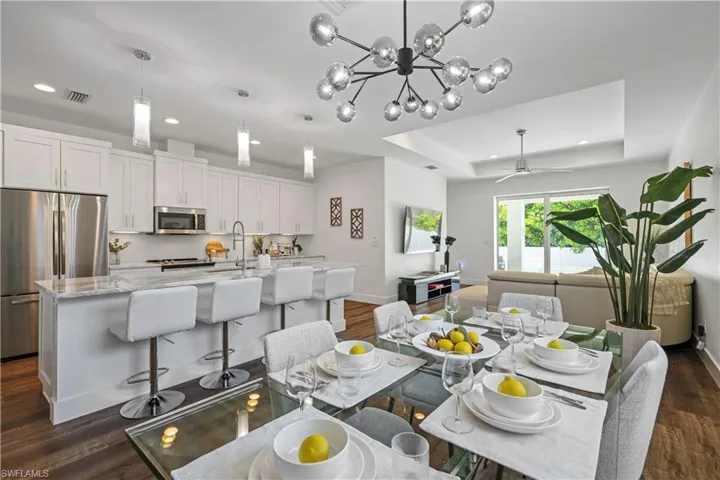 Dining area featuring recessed lighting, a chandelier, dark wood finished floors, ceiling fan, and a tray ceiling