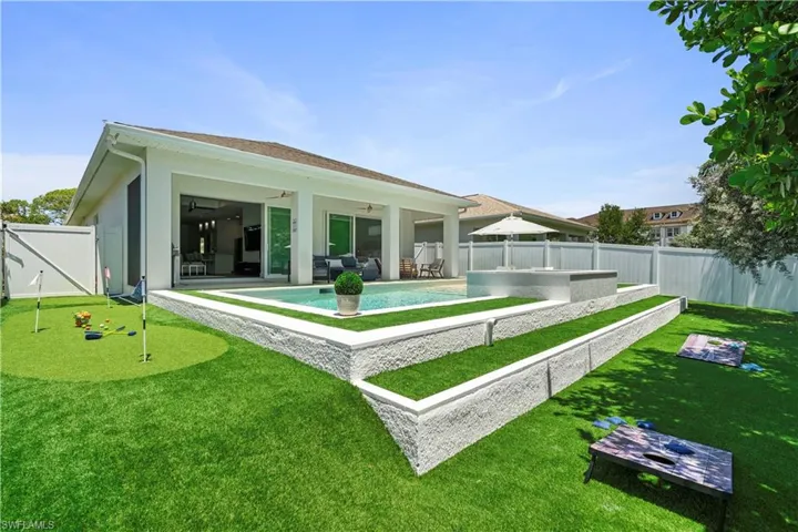 Back of property with an area to practice putting, a fenced backyard, a ceiling fan, a patio area, and stucco siding