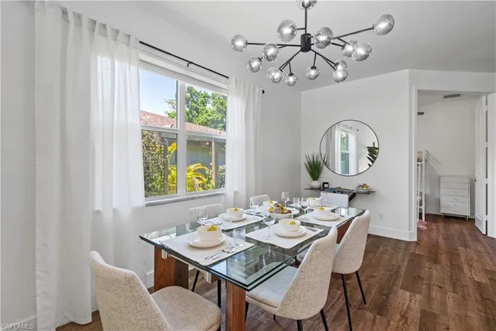 Dining space with plenty of natural light, dark wood finished floors, and a chandelier