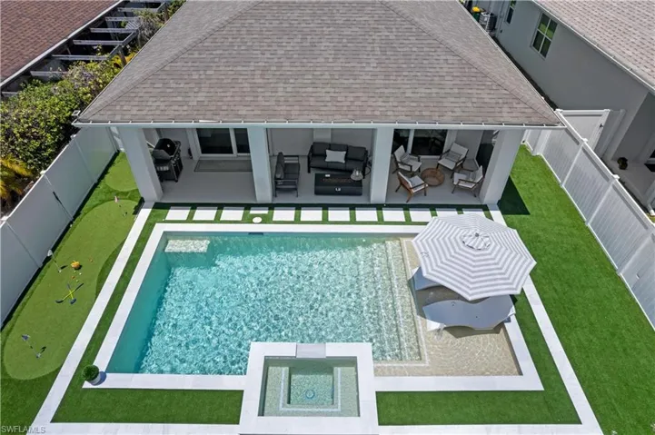 View of pool featuring a patio, a fenced backyard, a putting area, a pool with connected hot tub, and an outdoor hangout area