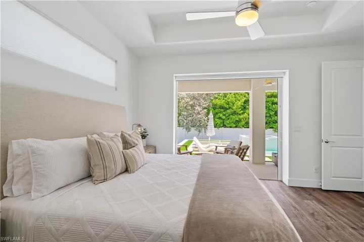 Bedroom with ceiling fan, wood finished floors, and access to exterior