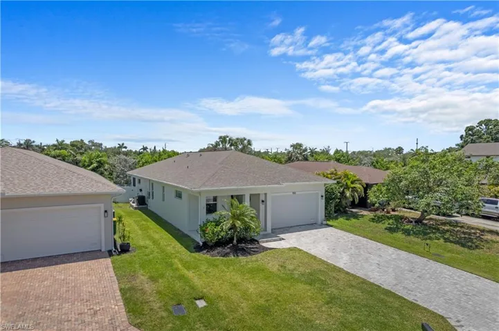 Single story home with a front yard, decorative driveway, stucco siding, and roof with shingles