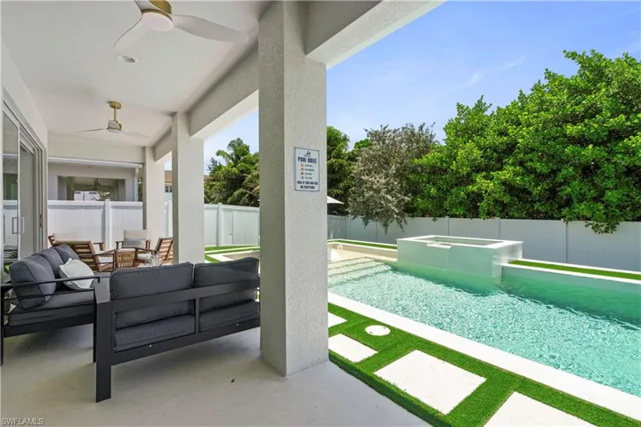 Fenced backyard with a patio area, outdoor lounge area, ceiling fan, and a pool with connected hot tub